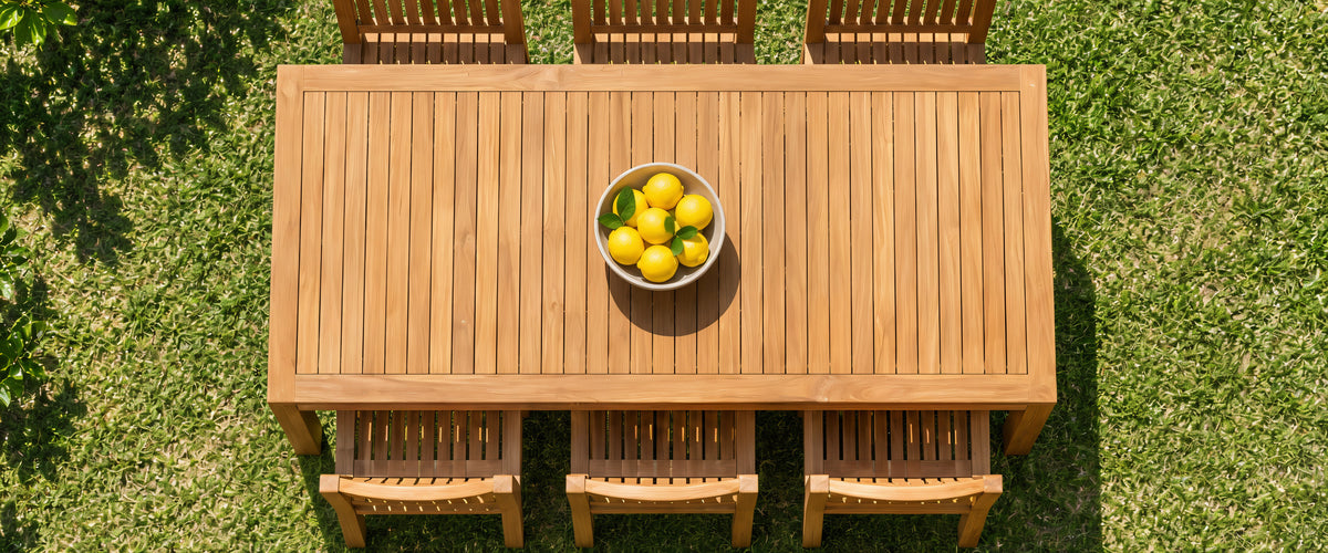 Teak dining table with six Tokyo chairs seen from above on a lawn, a bowl of lemons on the table