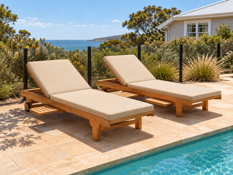 Two Extra Wide teak pool lounges with oatmeal cushions on sandstone paving in a coastal garden