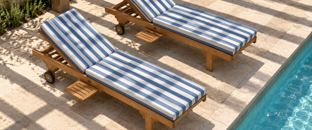 Two teak pool lounges with blue and white striped cushions beside a pool, pergola shadows falling across them
