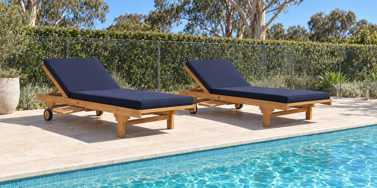 Two Extra Wide teak pool lounges with navy cushions along a backyard pool