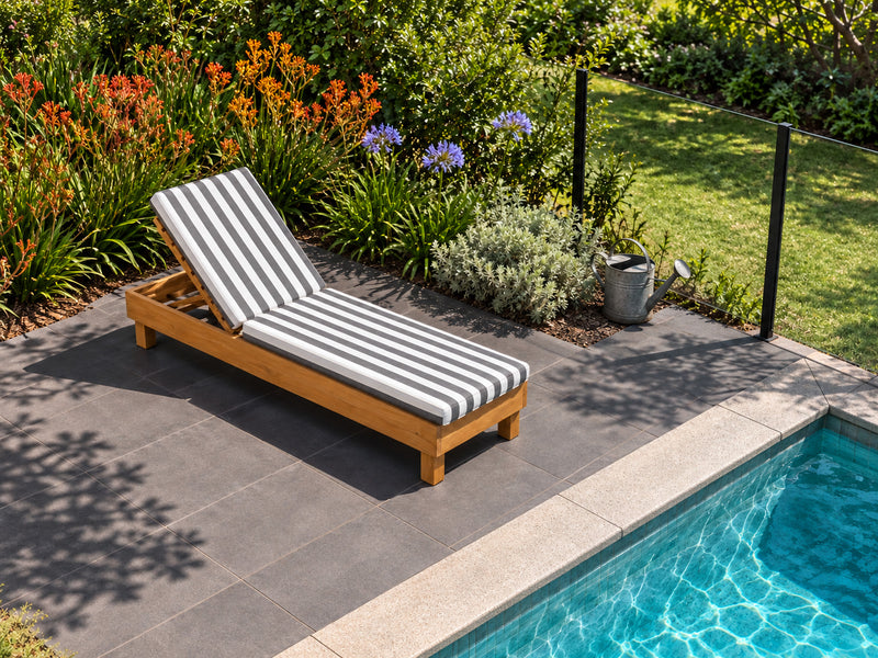 Portsea teak pool lounge with a denim stripe cushion beside a pool, with a border of kangaroo paw and agapanthus