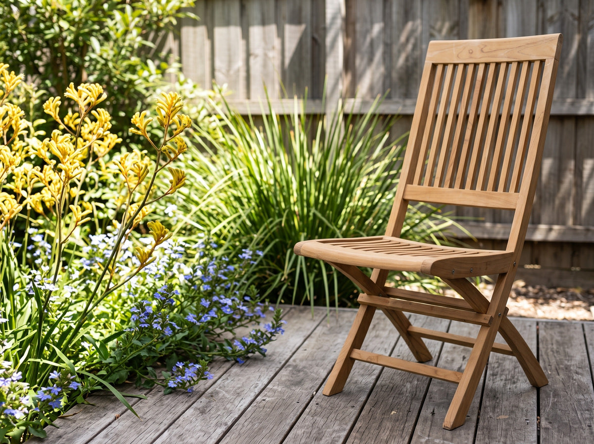 Teak Capri folding chair on a timber deck beside kangaroo paw and blue fan flower