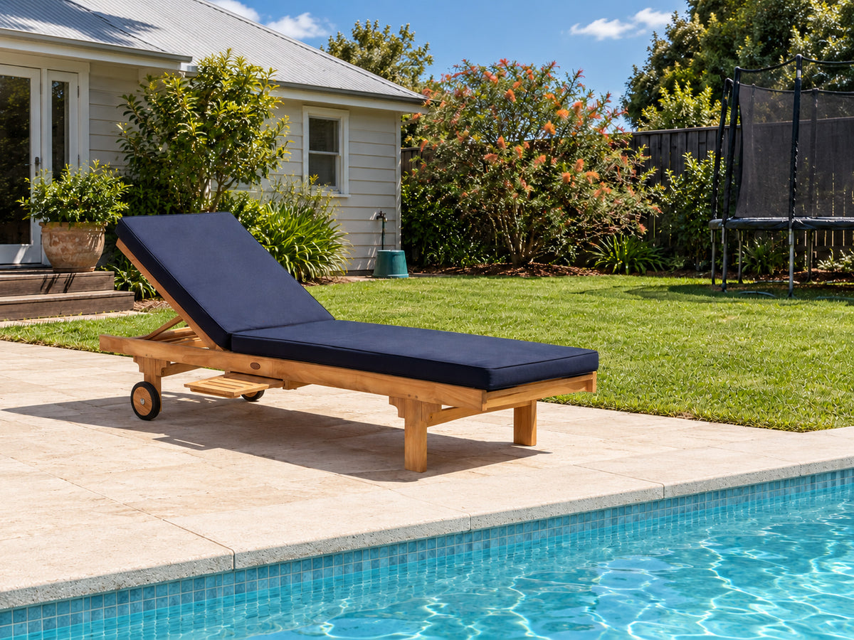 Traditional teak pool lounge with a navy cushion beside a pool in a family backyard
