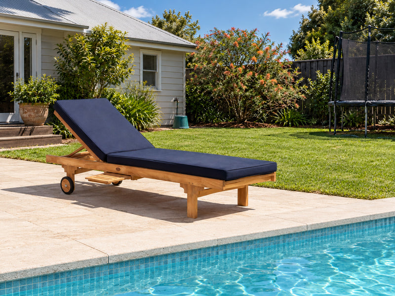 Traditional teak pool lounge with a navy cushion beside a pool in a family backyard