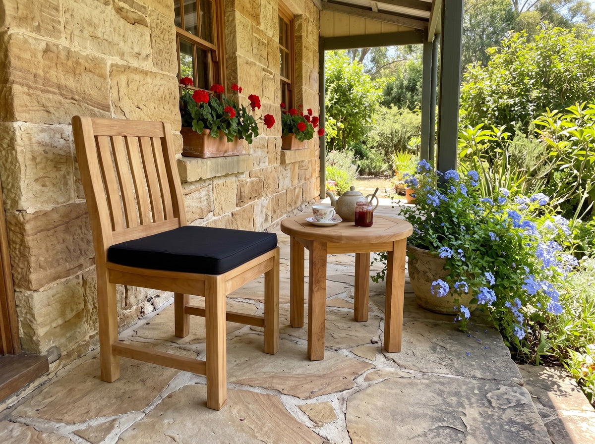 Teak Sierra dining chair with black cushion and a round teak side table on a sandstone cottage verandah