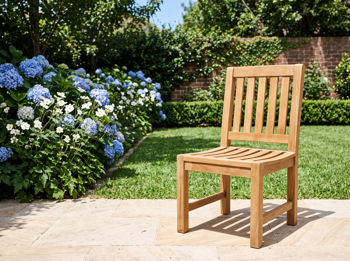 Teak Sierra dining chair on a sandstone terrace beside blue hydrangeas